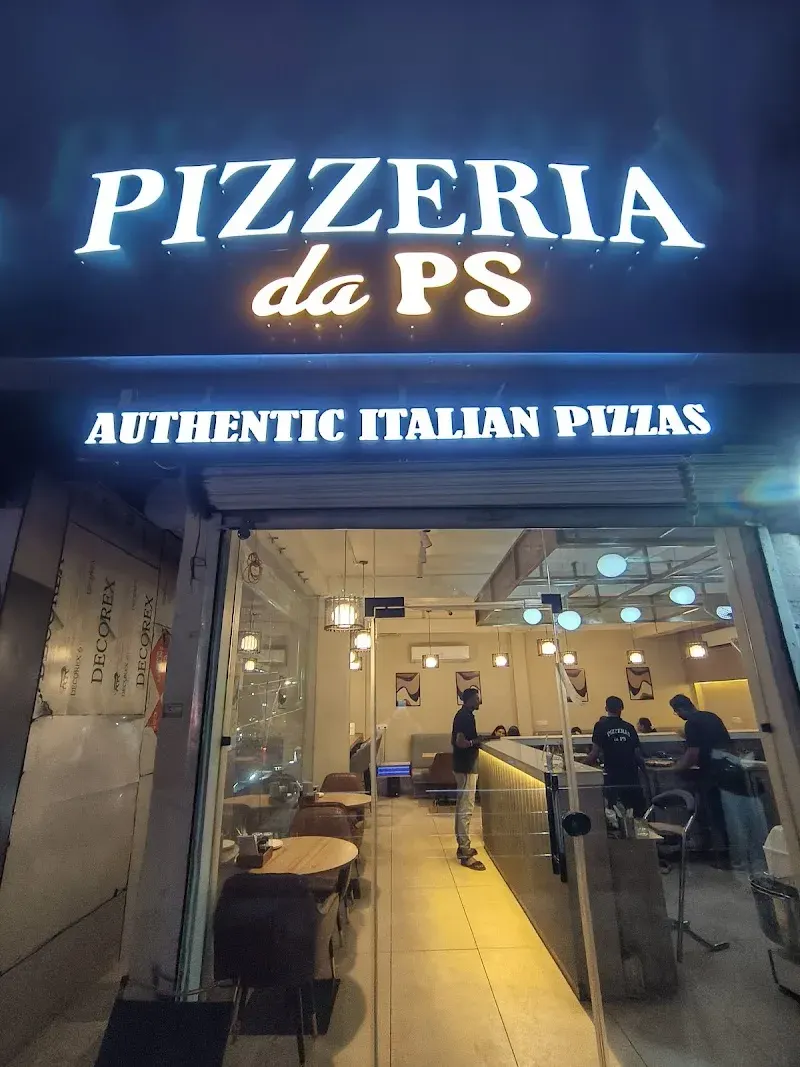 The lit Pizzeria da PS sign over the entrance at night